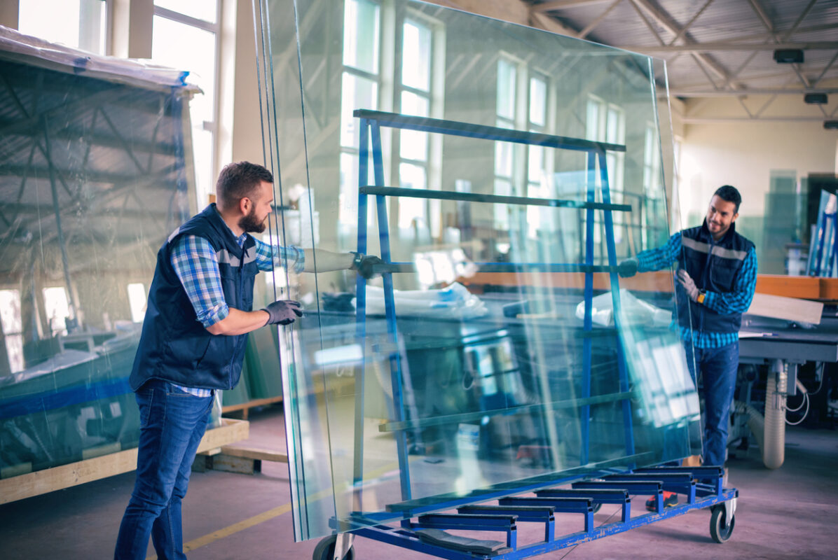 Workers packaging glass sheets in warehouse